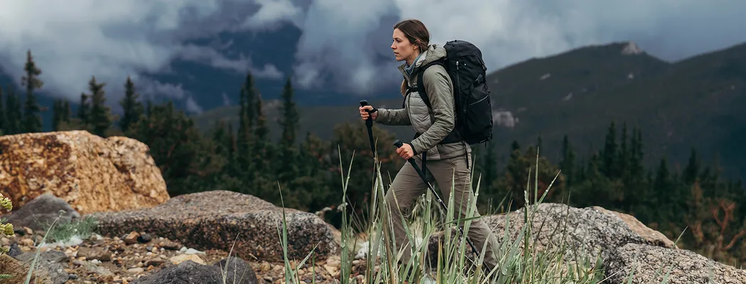 Туристка с треккинговыми палками на горном маршруте